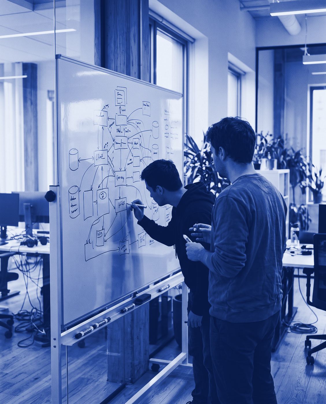 Two engineers sketching a system architecture on a whiteboard